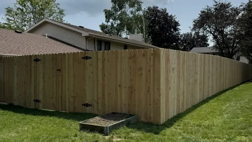 Wooden privacy fence enclosing a backyard beside a house, with a small raised platform in front