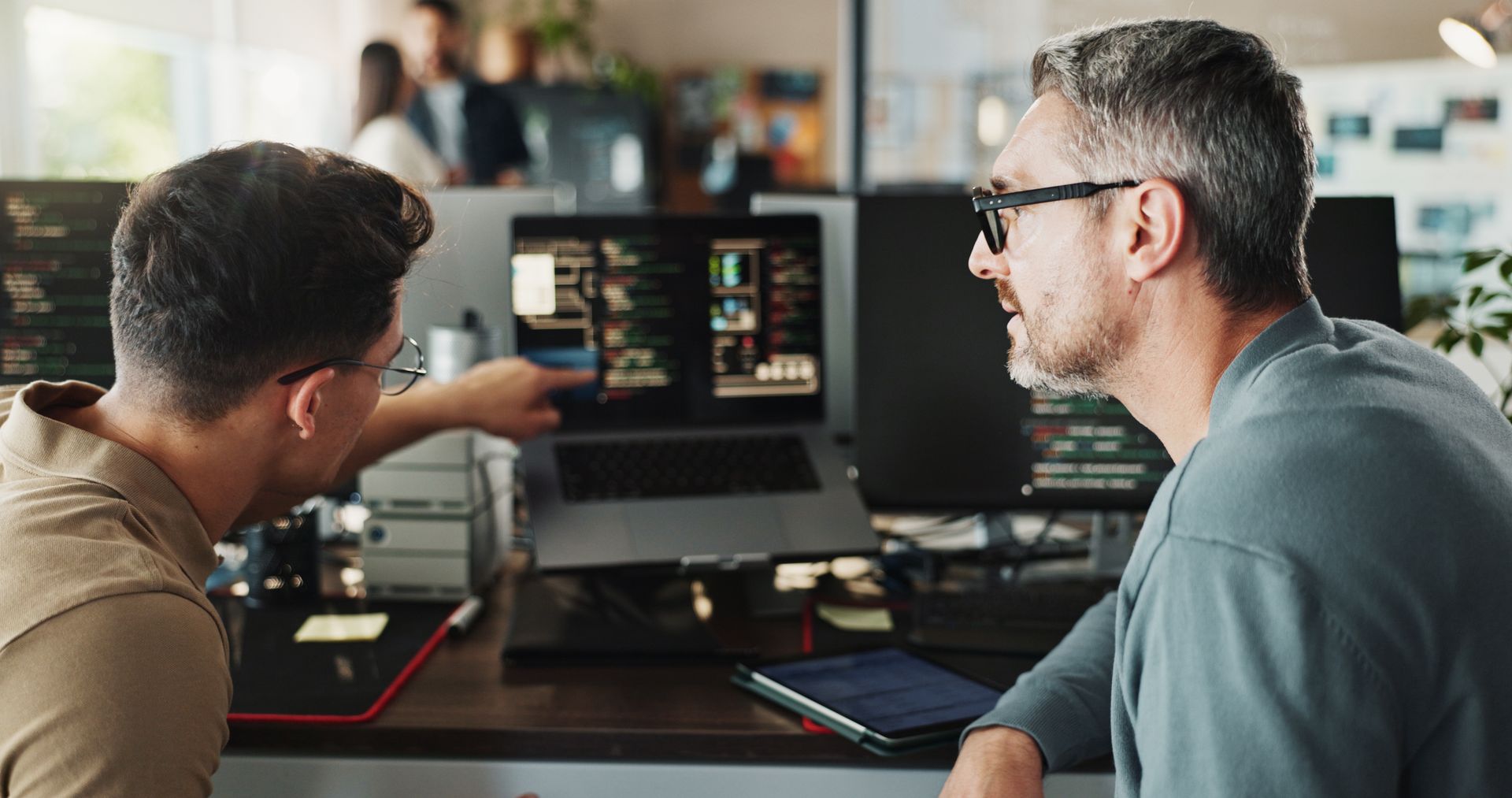 Two people reviewing video footage on computer monitors in an editing workspace