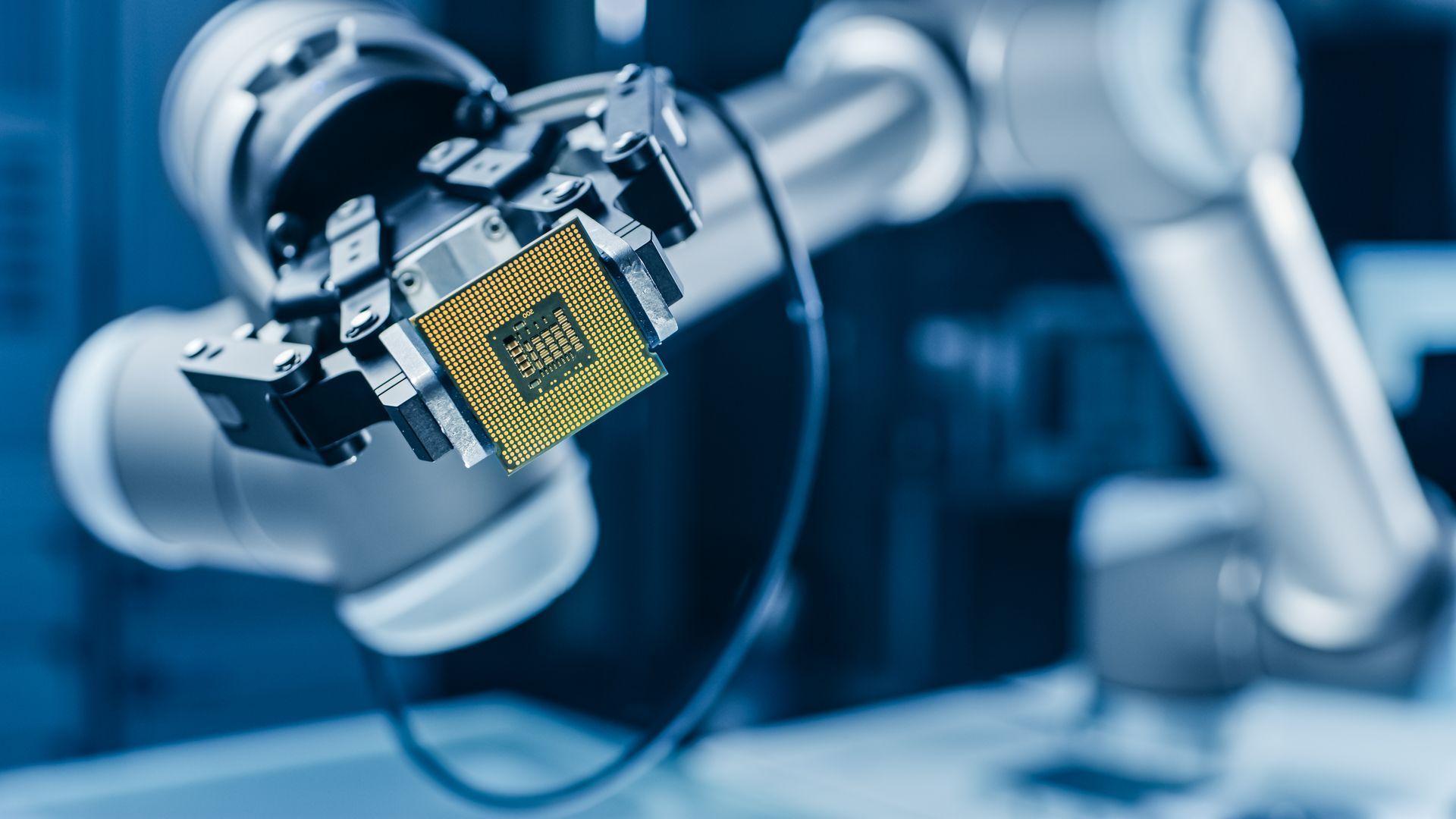 Robotic arm holding a microchip in an automated electronics assembly line
