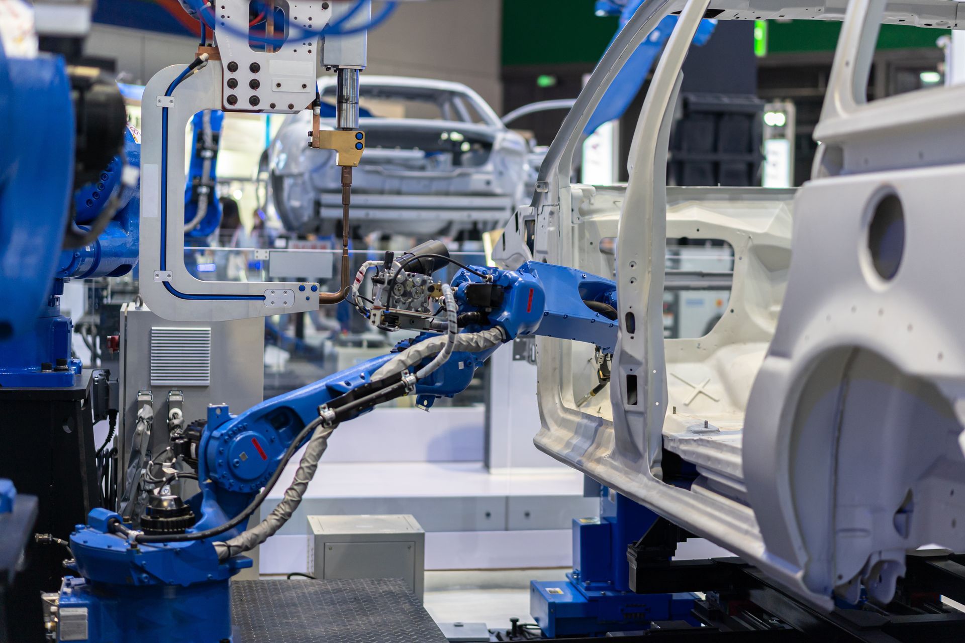 Blue robotic arms assembling white car parts in an automated factory line