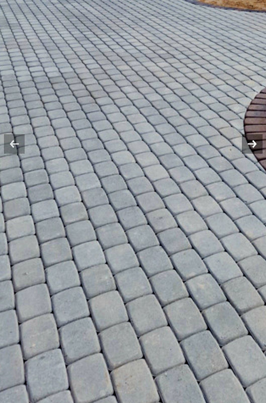 Pilkų plytų takas su mediniu suoliuku fone