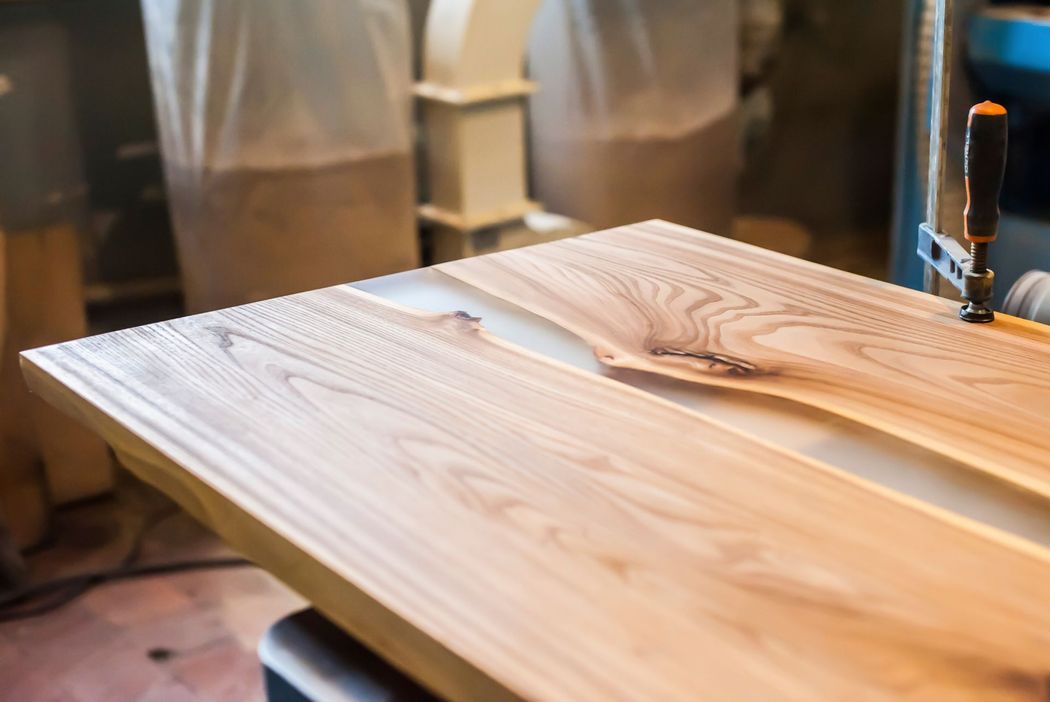 Piano di legno levigato o rifinito in un laboratorio, con attrezzi e luci calde sullo sfondo