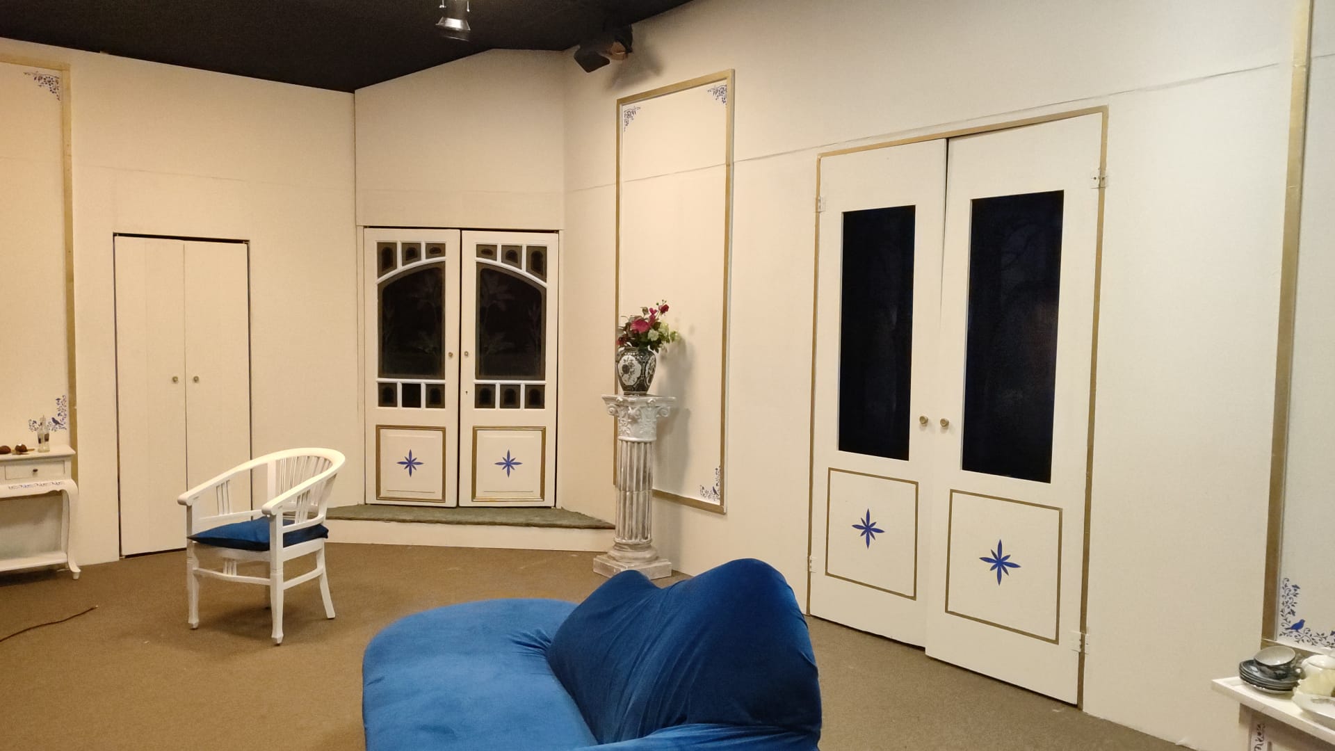 De tante van Charlie. Interieur van een kamer, witte muren, blauwe bank en stoel, sierlijke deuren en details.