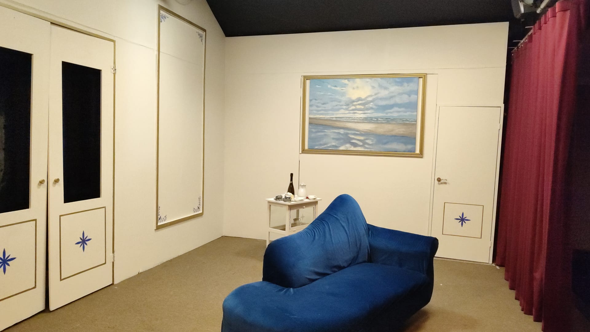 De tante van Charlie. Een kamer met een blauwe chaise longue, een ingelijst schilderij en twee deuren.