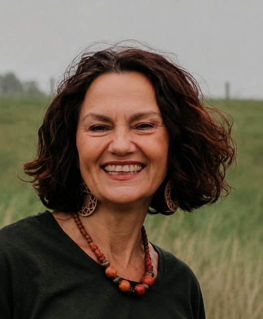 Conny van der Heul. Een lachende vrouw met donker haar, staat buiten bij water en groen.