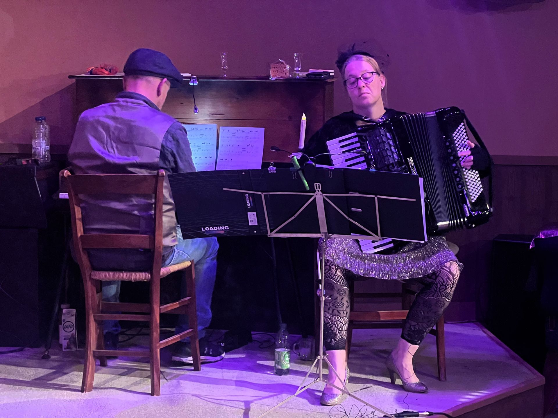 Rooie Sien. In een schemerig verlichte ruimte speelt een muzikant accordeon, terwijl een ander piano speelt.