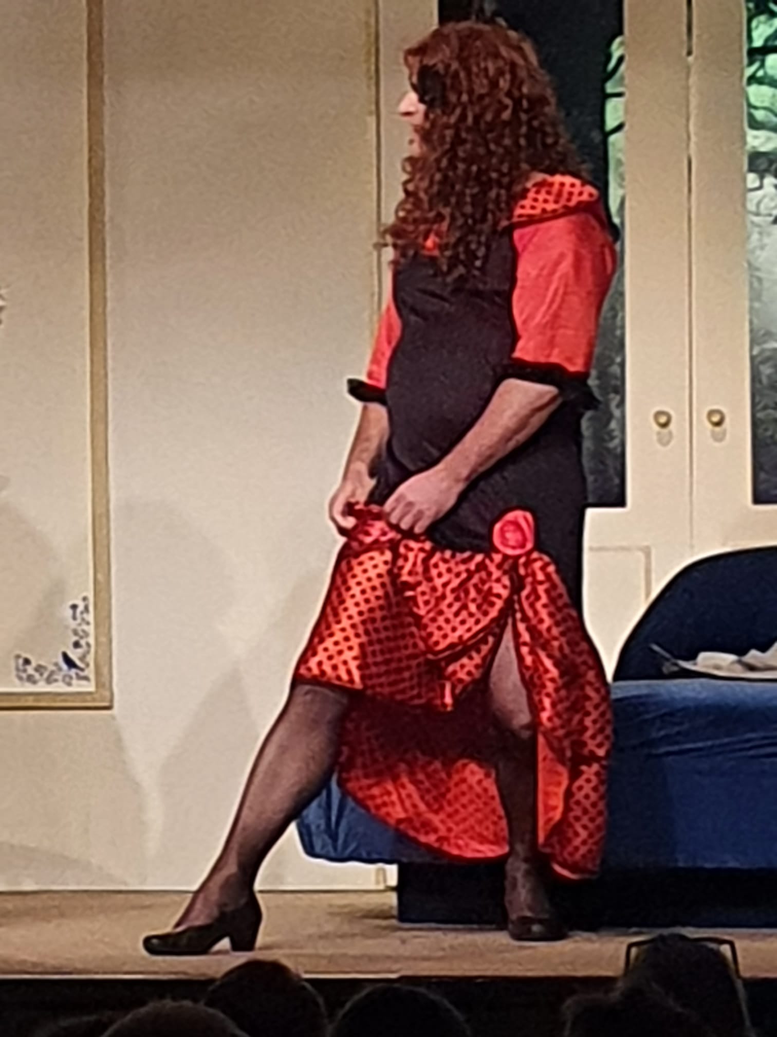 De tante van Charlie. Brasschaet in travestie, gekleed in een rood-zwarte jurk en pruik.