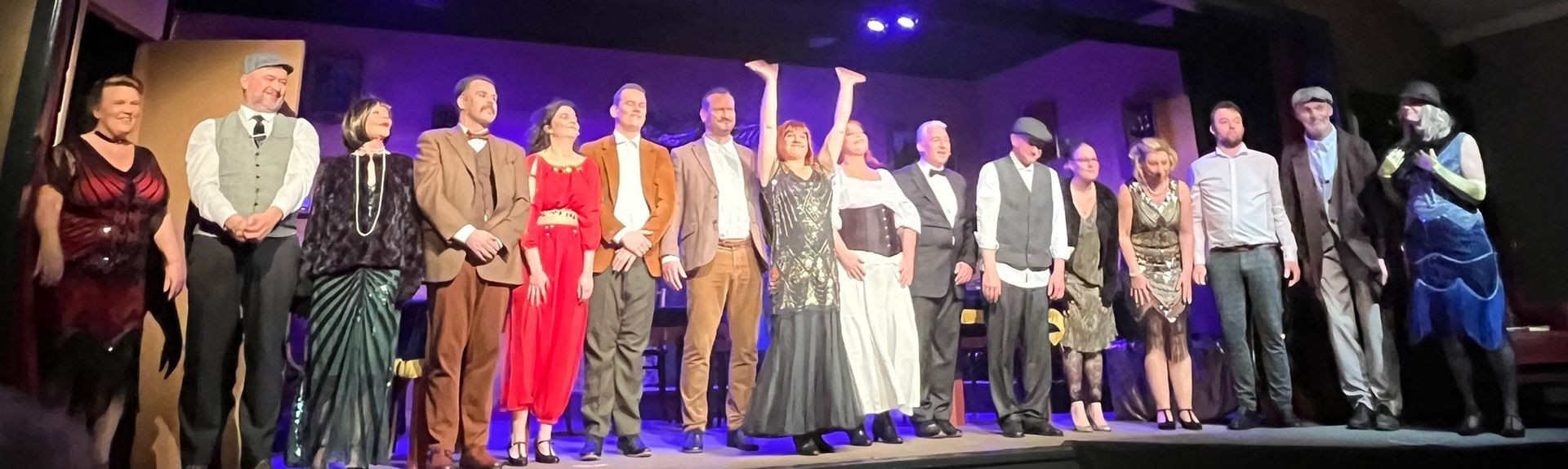 Rooie Sien. Een groep mensen in kleding uit de jaren twintig staat op een podium. Eén persoon heft zijn armen omhoog.