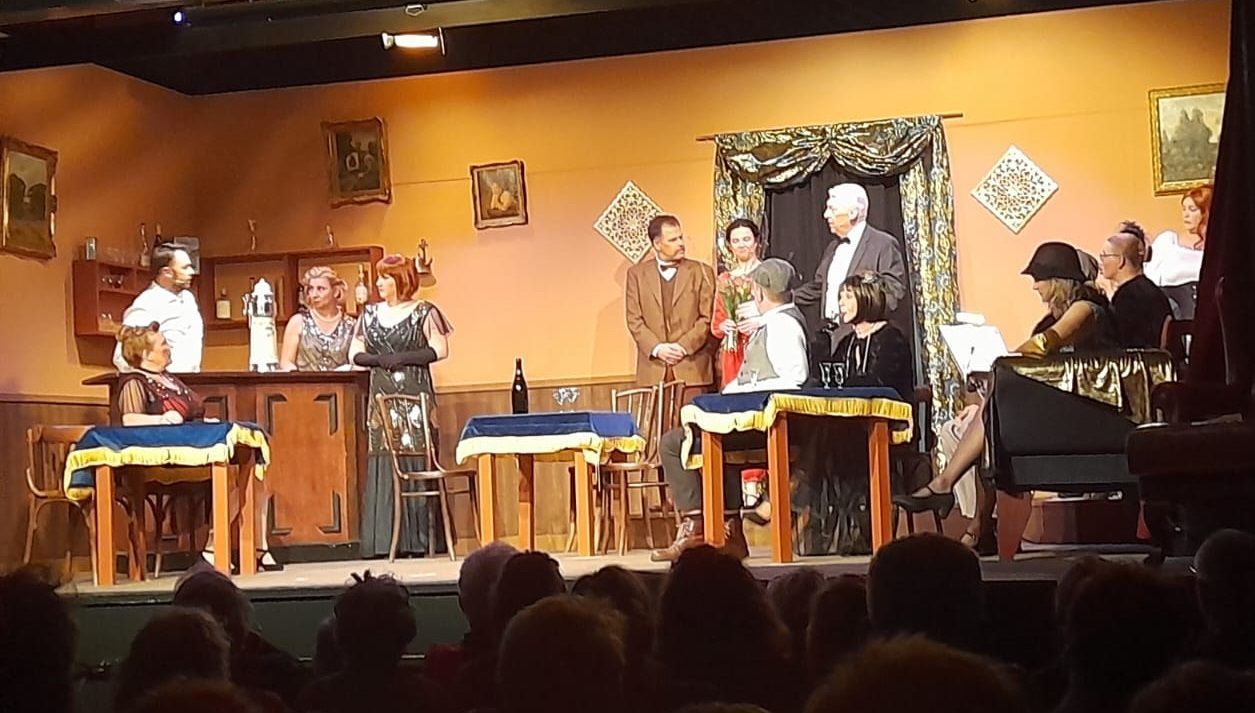Rooie Sien. Toneelstuk met acteurs in kostuums in een vintage decor. Publiek zit op de voorgrond.