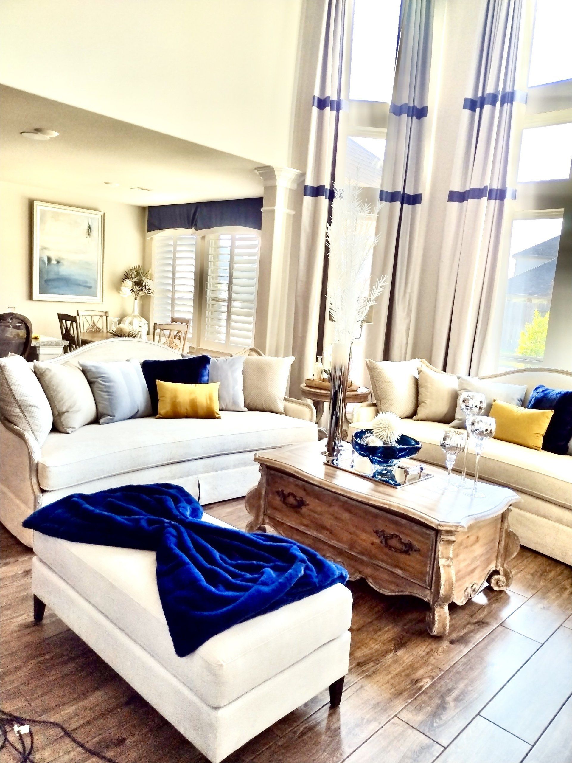 A living room with two beige sofas, a wooden coffee table, and an ottoman draped with a bright blue throw blanket.