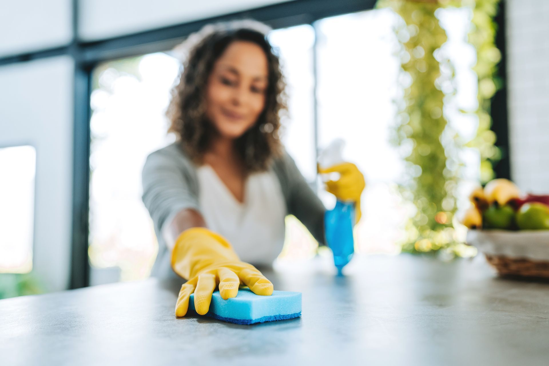 Young cleaning maid woman cleaning a countertop, with a zoom on her hand.