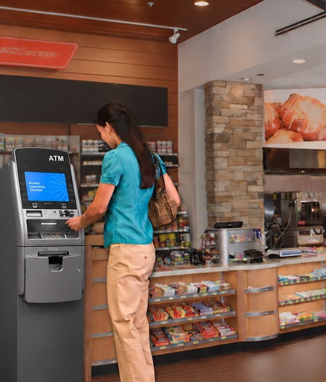Woman using a retail ATM inside a convenience store, providing convenient cash access for shoppers in Alton, IL.