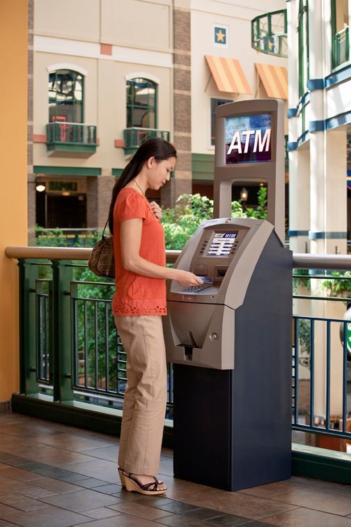 Woman using a retail ATM at a shopping center, highlighting convenient cash access and free ATM placement for Ballwin, MO businesses.