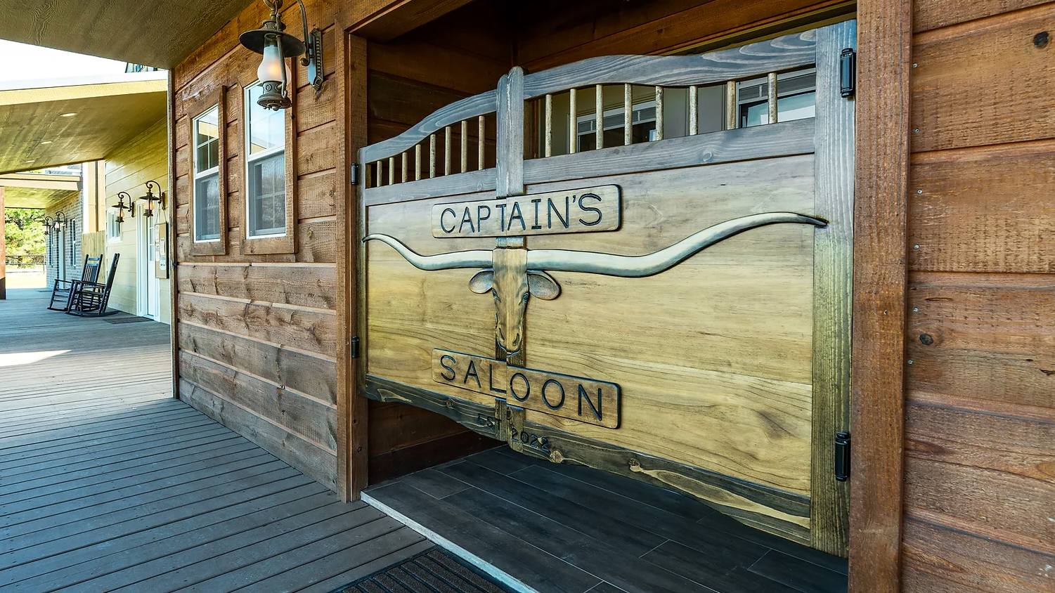 A wooden doorway featuring swinging saloon-style doors with a decorative longhorn skull and the text