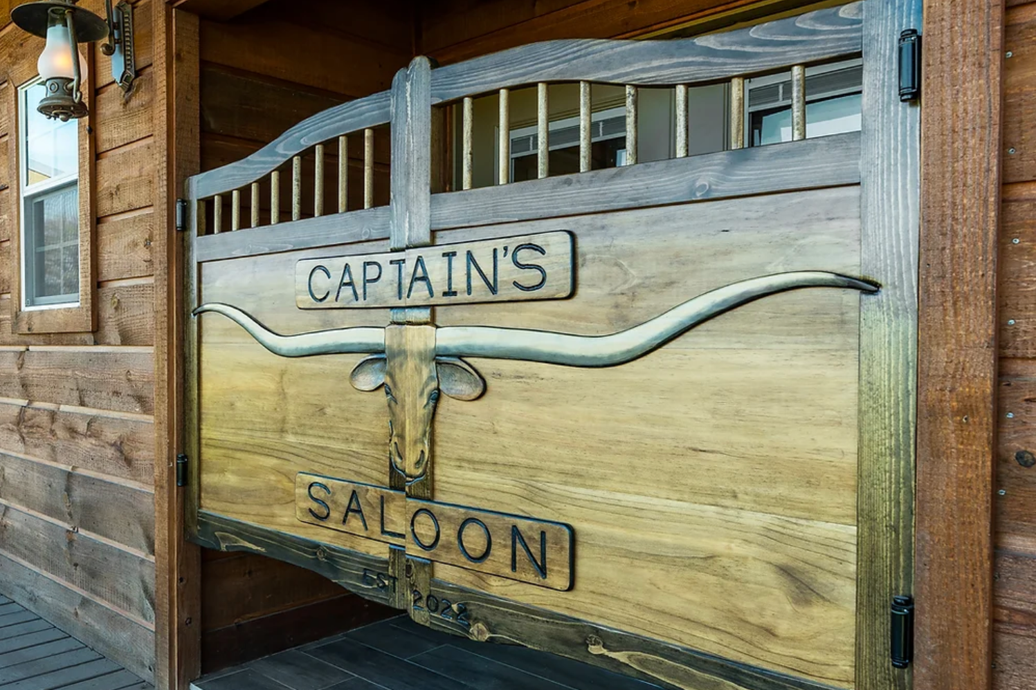 A wooden swinging saloon door with long horns and the text