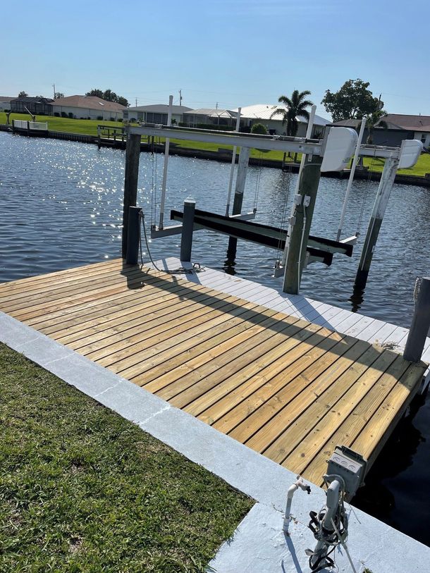 Small wooden dock with railings extending over a calm waterfront under a sunny sky Small wooden dock with railings extending over a calm waterfront under a sunny sky