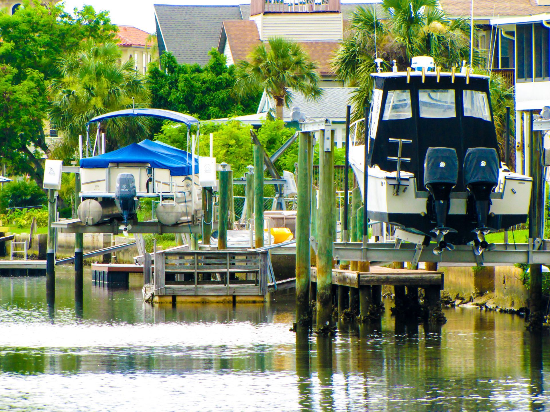 Canal with docked boats, wooden piers, and houses along a calm waterfront in bright daylight Canal with docked boats, wooden piers, and houses along a calm waterfront in bright daylight