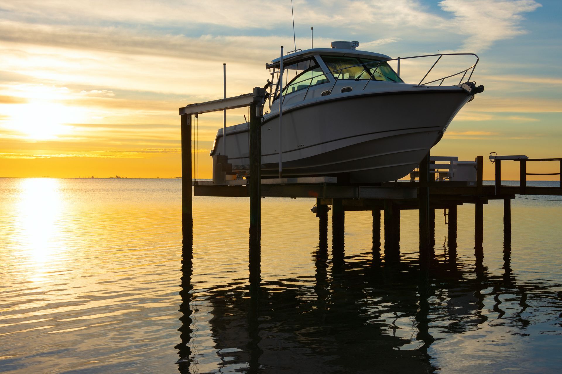 Boat on a lift at sunset over calm water, with golden sky reflections. Boat on a lift at sunset over calm water, with golden sky reflections.
