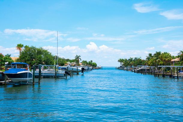 Sunny marina canal with boats, docks, and palm trees under a blue sky Sunny marina canal with boats, docks, and palm trees under a blue sky
