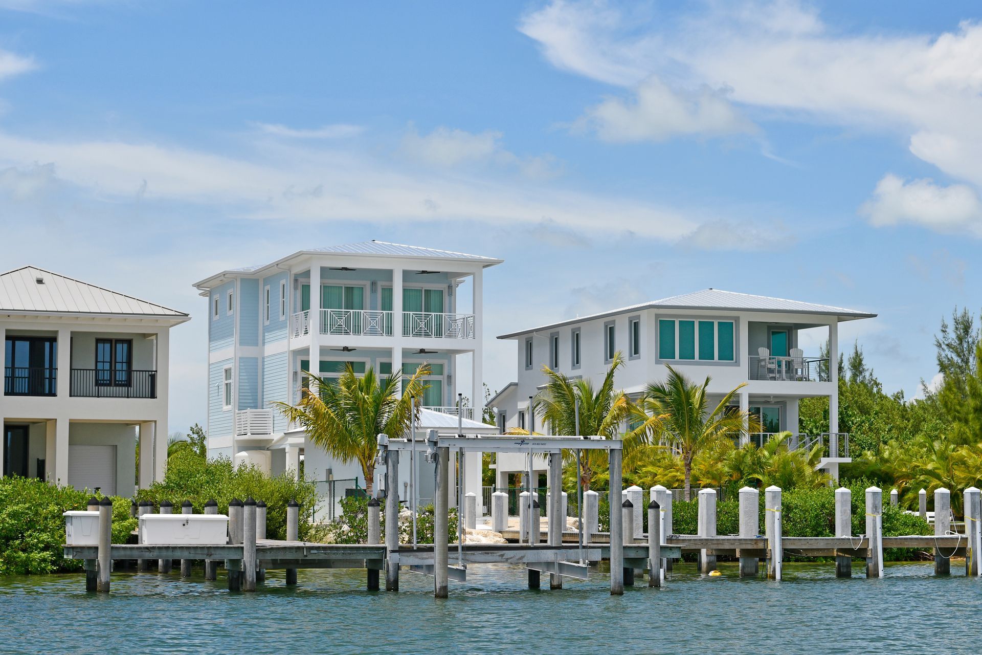 Modern waterfront homes with docks and palm trees under a blue sky Modern waterfront homes with docks and palm trees under a blue sky