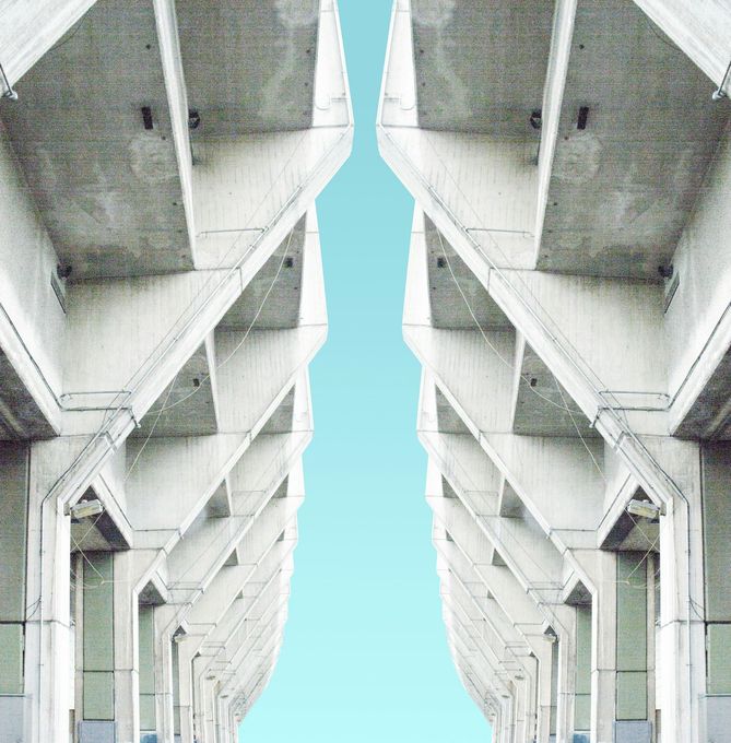 Symmetrical concrete bridge supports framing a bright blue sky corridor