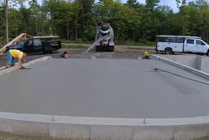Contractors are pouring and smoothing out the concrete slab.