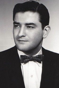 Black-and-white studio portrait of a man in a suit and bow tie, looking to the side.