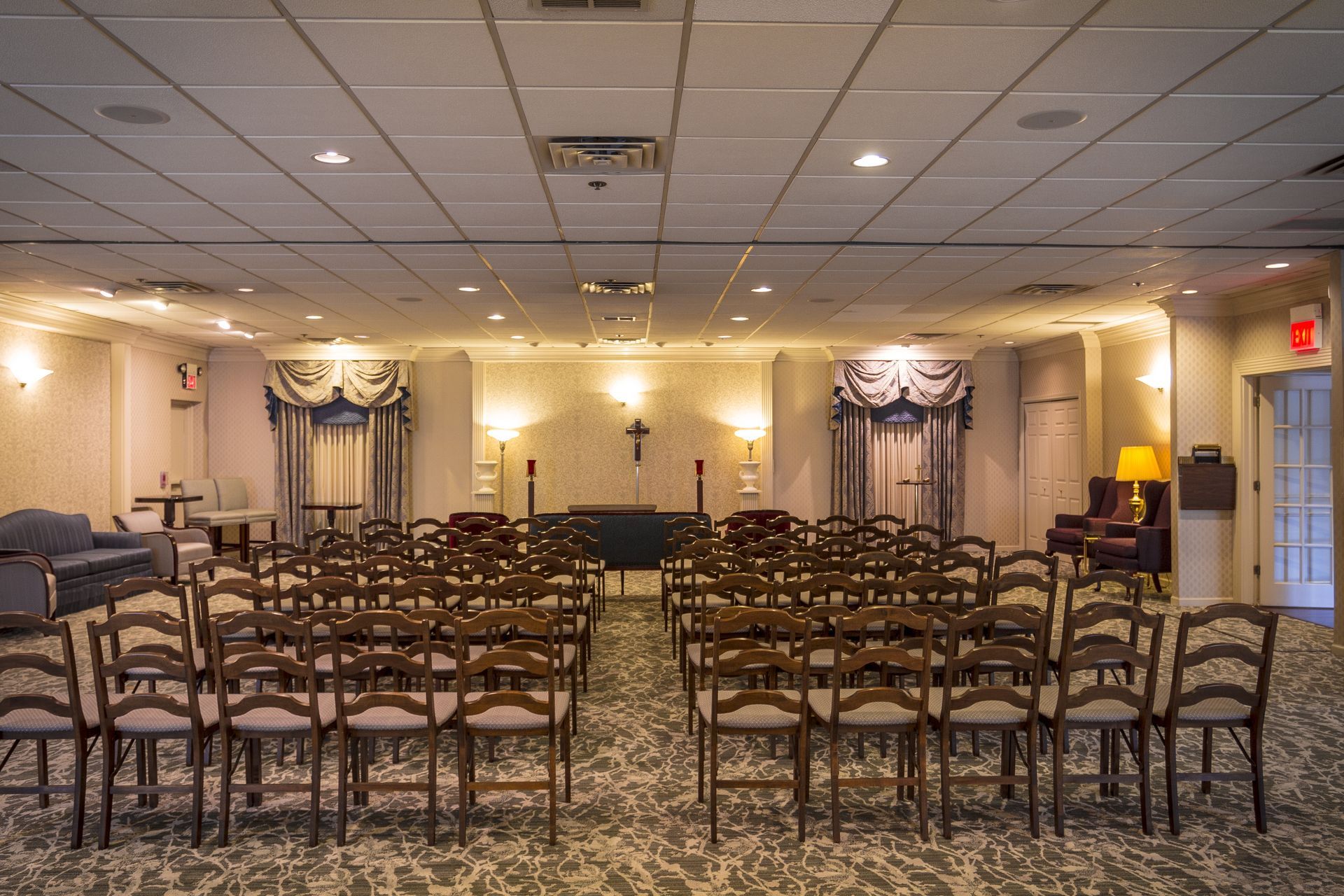Empty banquet hall with rows of chairs facing a small stage and decorative drapes