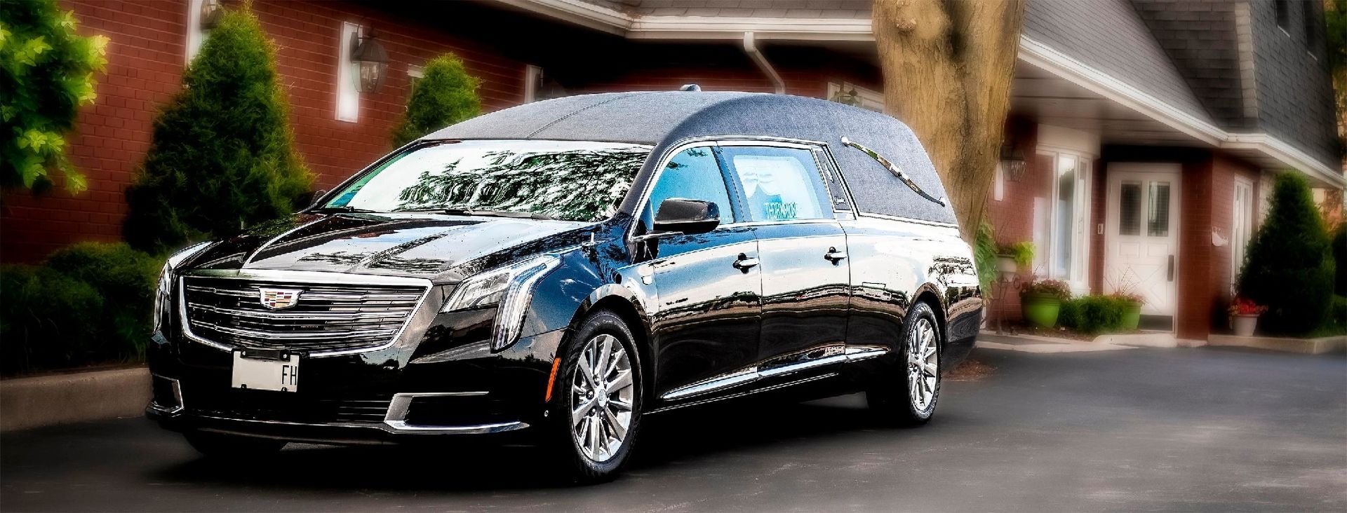 Black Cadillac sedan parked in a suburban driveway with a blurred house in the background