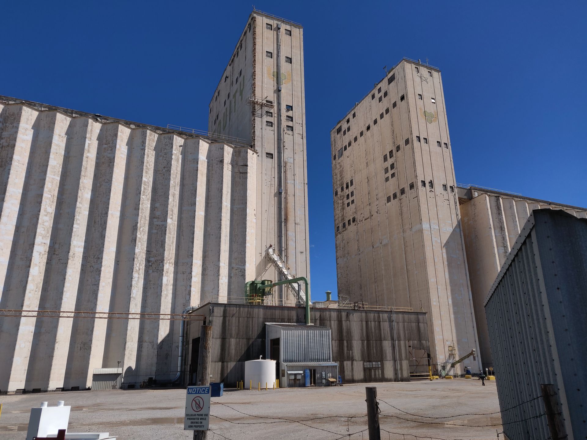 Industrial grain silos and striped storage buildings under a clear blue sky