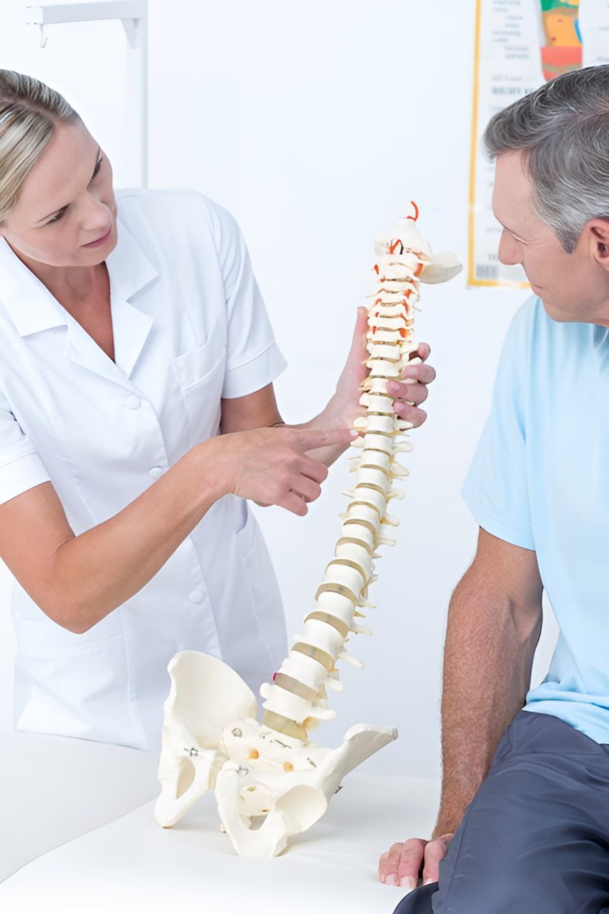A Nurse Is Showing A Man A Model Of A Spine — Back In Motion Chiropractic & Healthcare In Tully, QLD