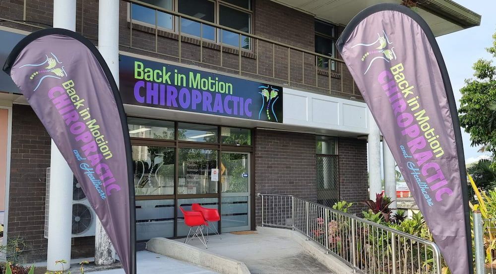 Two Flags Are Flying In Front Of A Building — Back In Motion Chiropractic & Healthcare In Innisfail, QLD