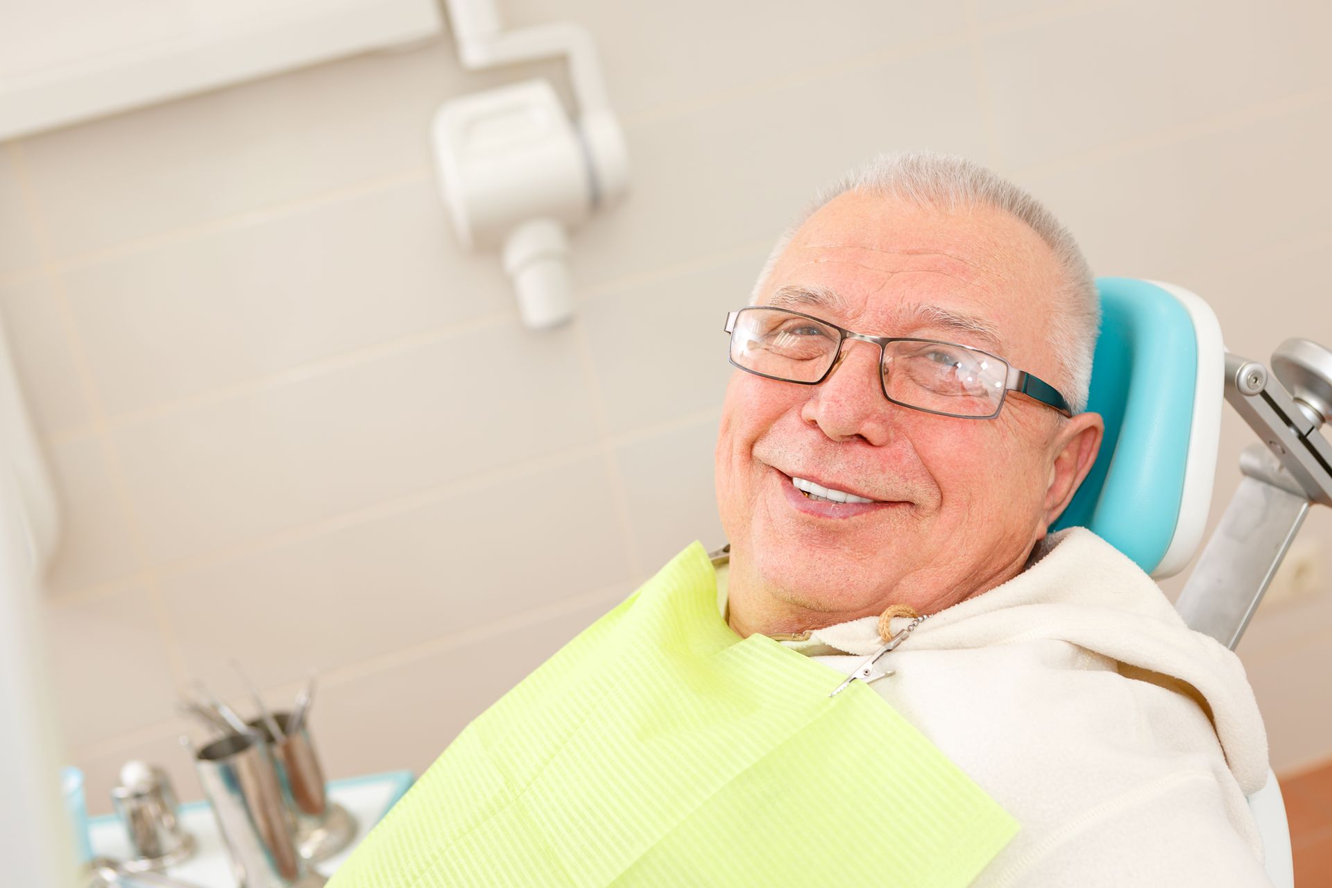 Dentist in white coat and mask examining a tooth model while speaking with a patient in a clinic