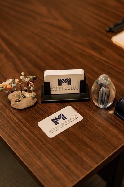 Wooden desk with a business card holder, branded card, and small decorative objects