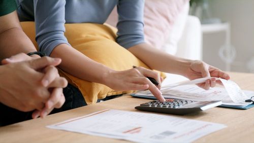 People reviewing paperwork and using a calculator at a table.