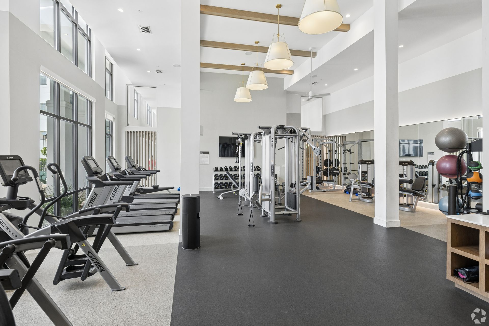Bright gym interior with cardio machines, weight equipment, and high ceilings