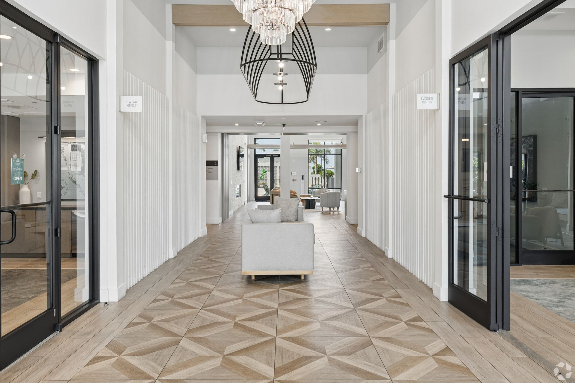 Bright modern hallway with glass doors, white walls, patterned carpet, and a central white bench.