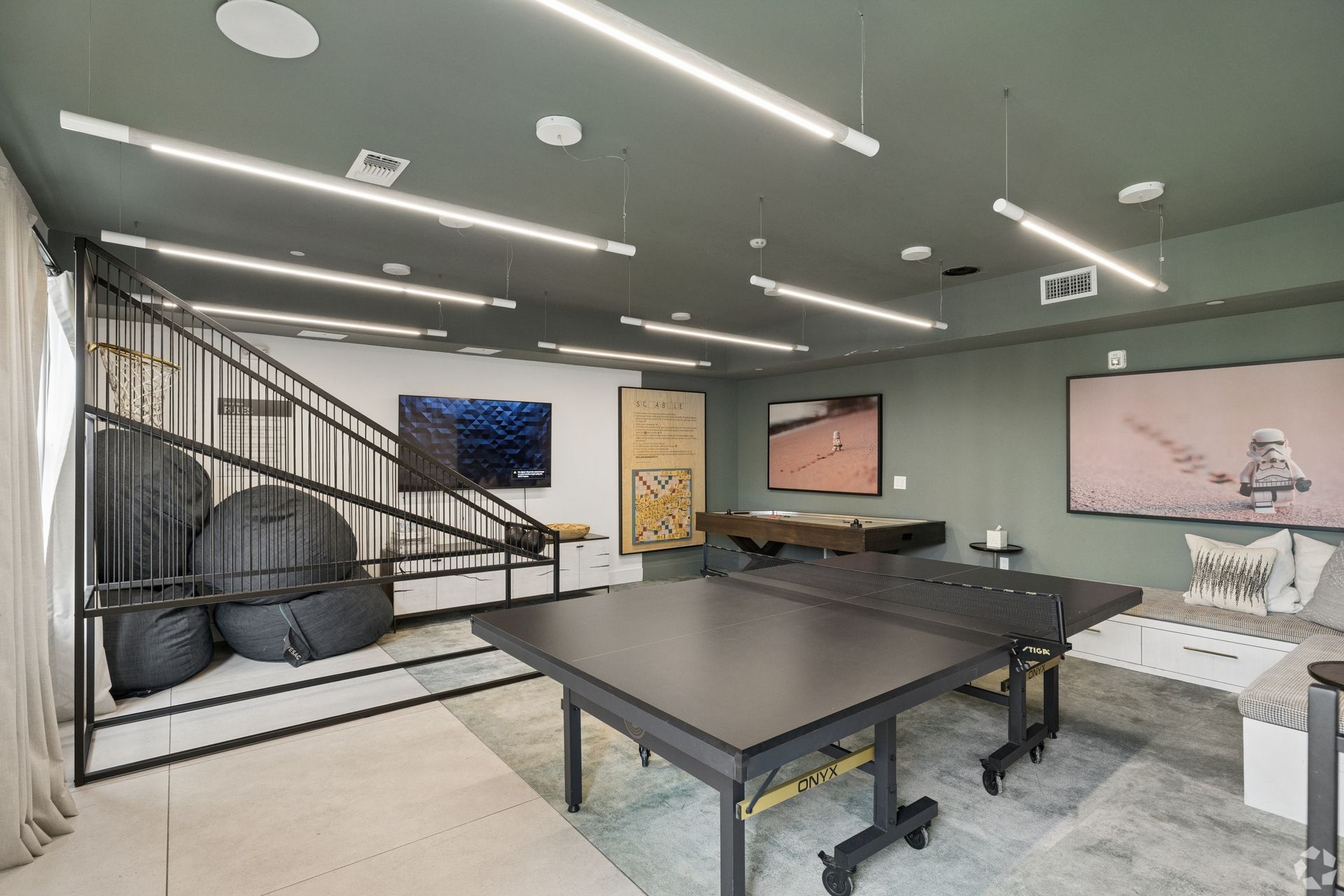 Modern game room with ping-pong table, stairs, couch, and wall-mounted TV