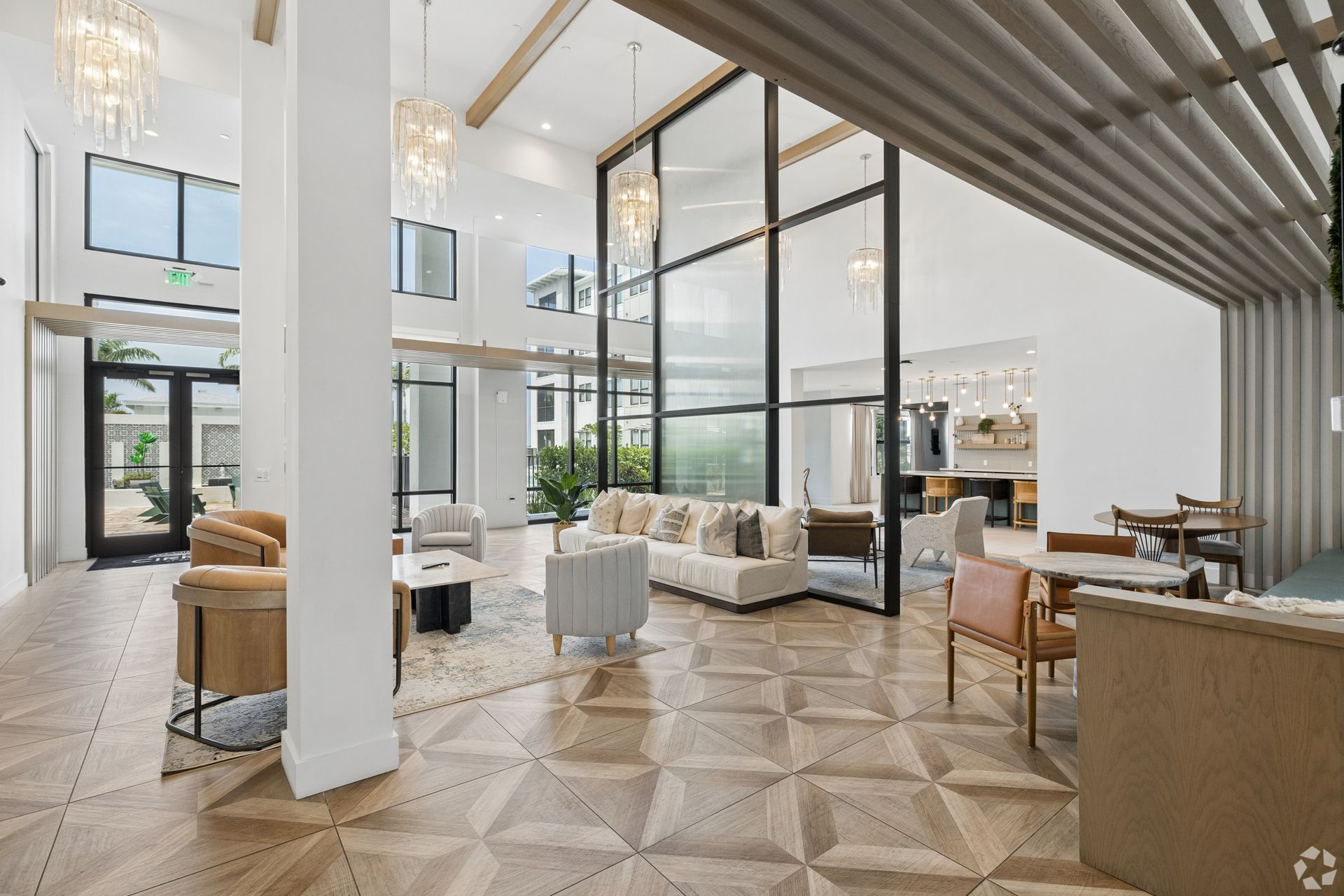 Modern open-plan living room with large glass walls, white furnishings, and patterned tile floor