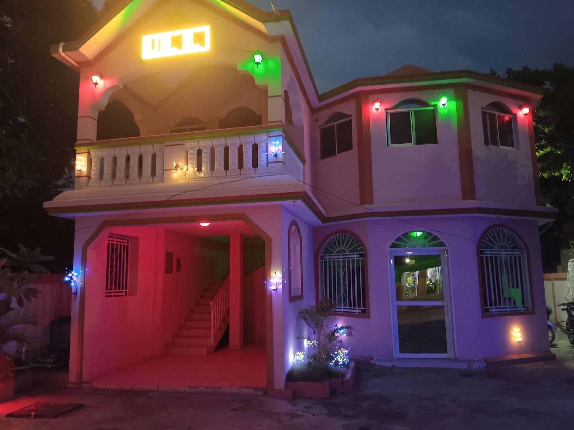 Two-story house lit with colorful Christmas lights at night