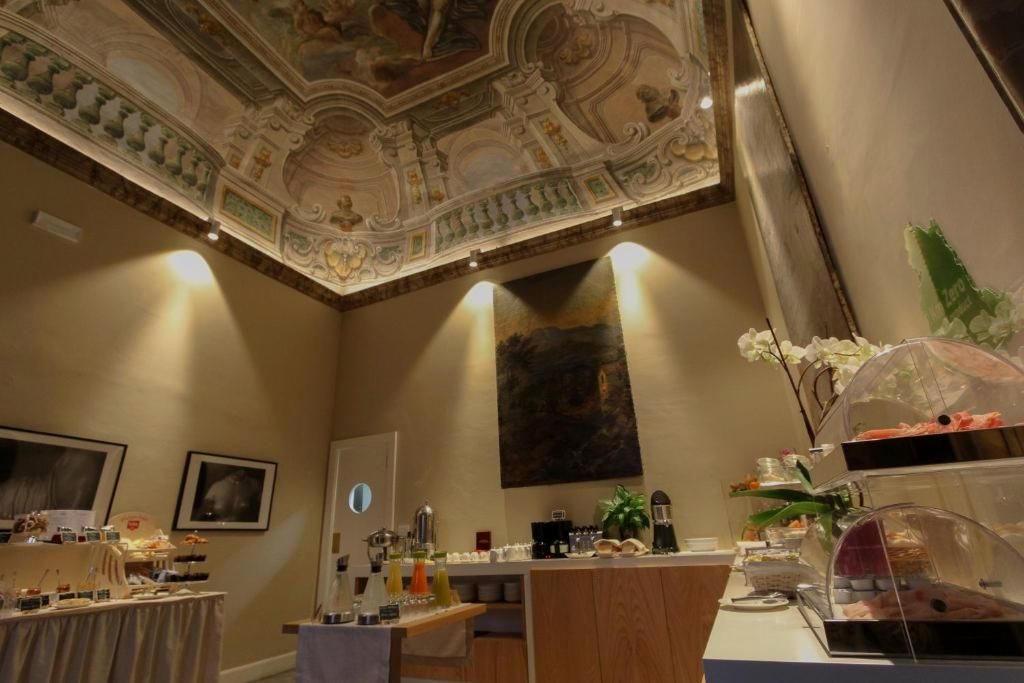 Sala decorata con soffitto dipinto, buffet con cibo e piccolo bar.