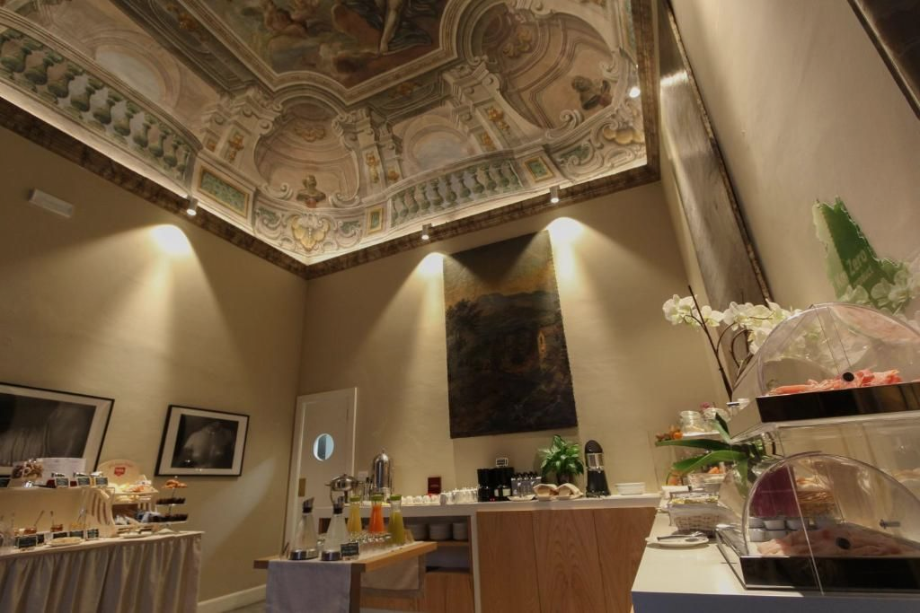 Soffitto decorato in una stanza con bancone per il servizio. Sono visibili espositori e un dipinto.