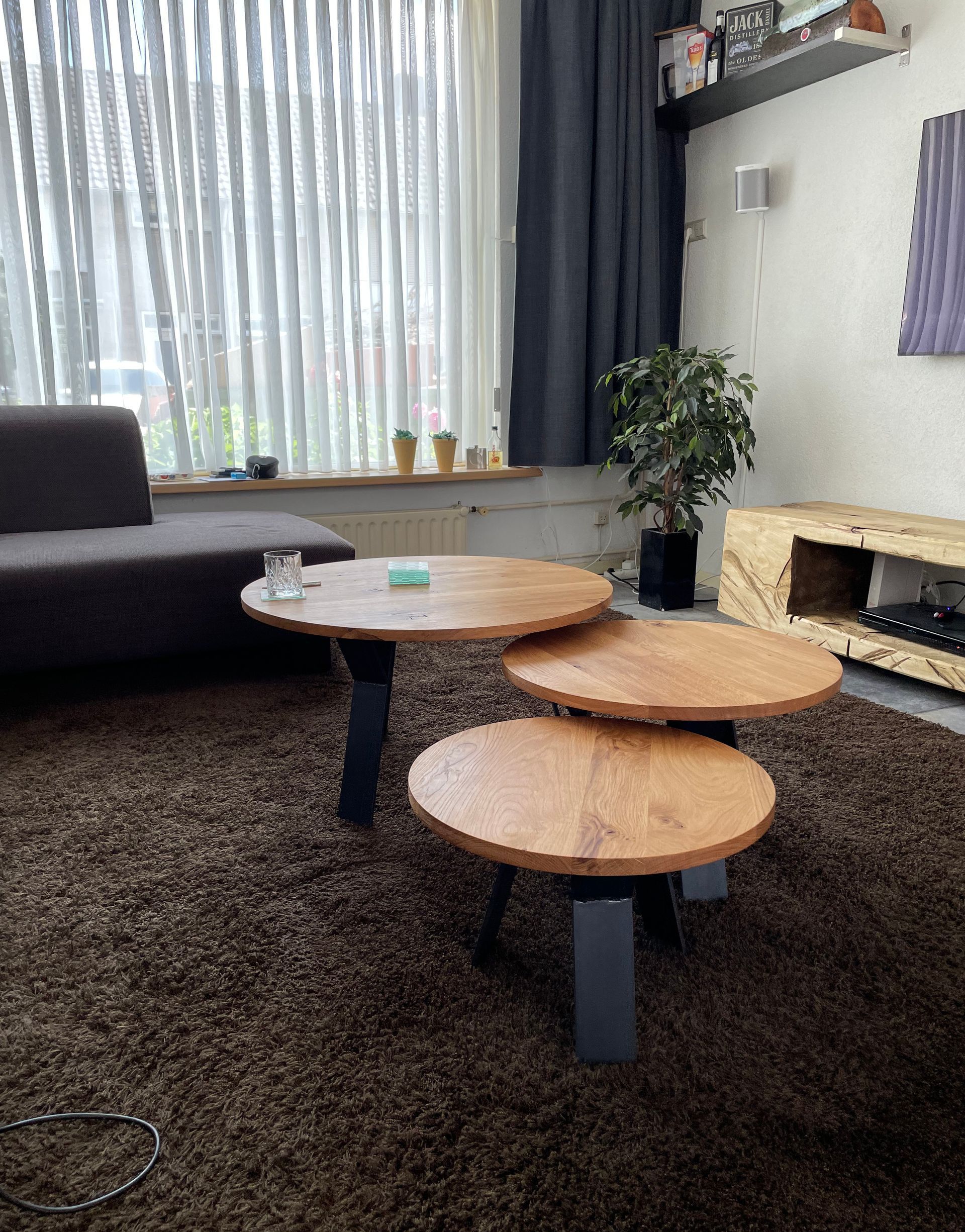 Een woonkamer met drie houten tafels en een bank.