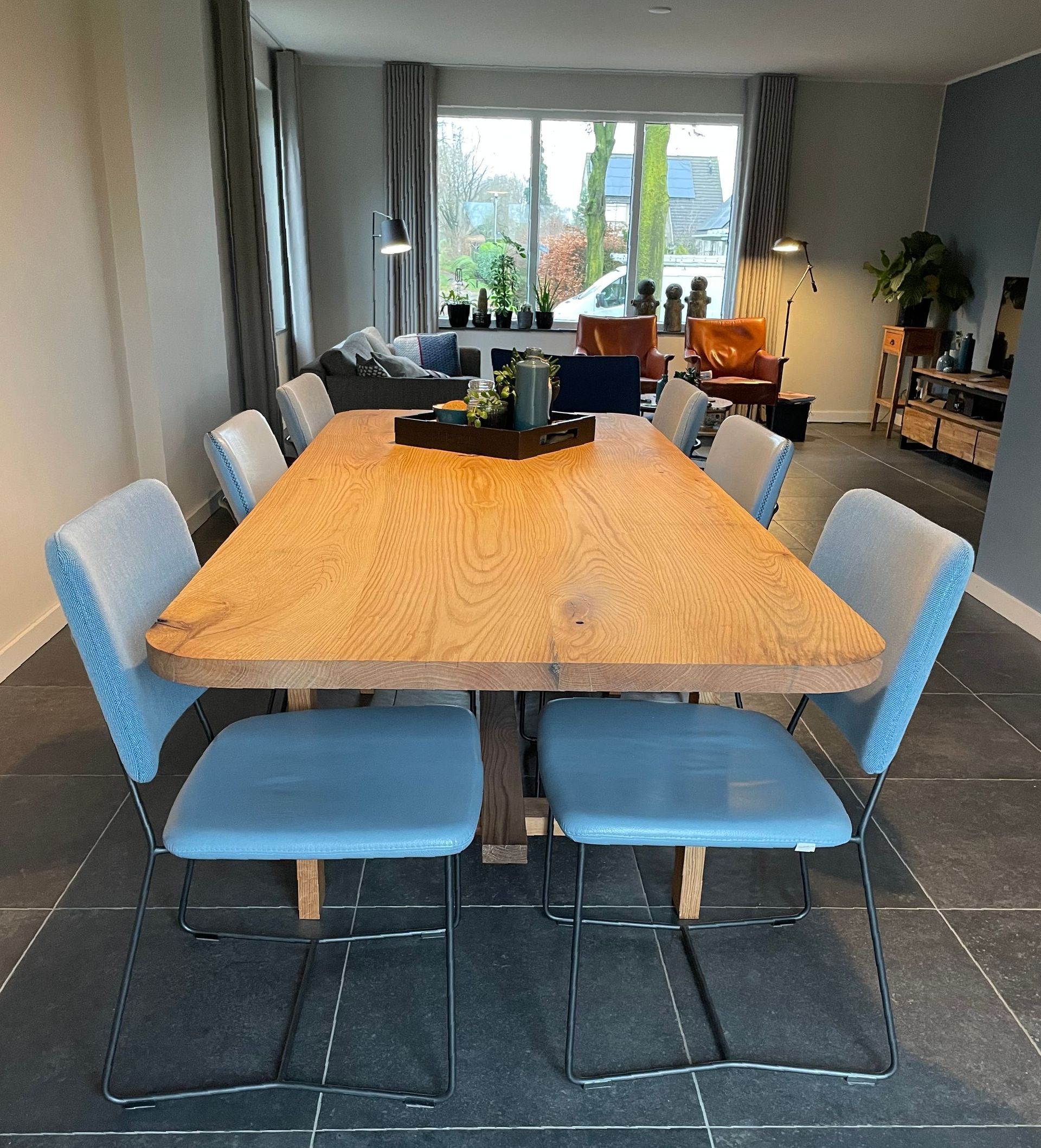 Een houten tafel met blauwe stoelen in een woonkamer
