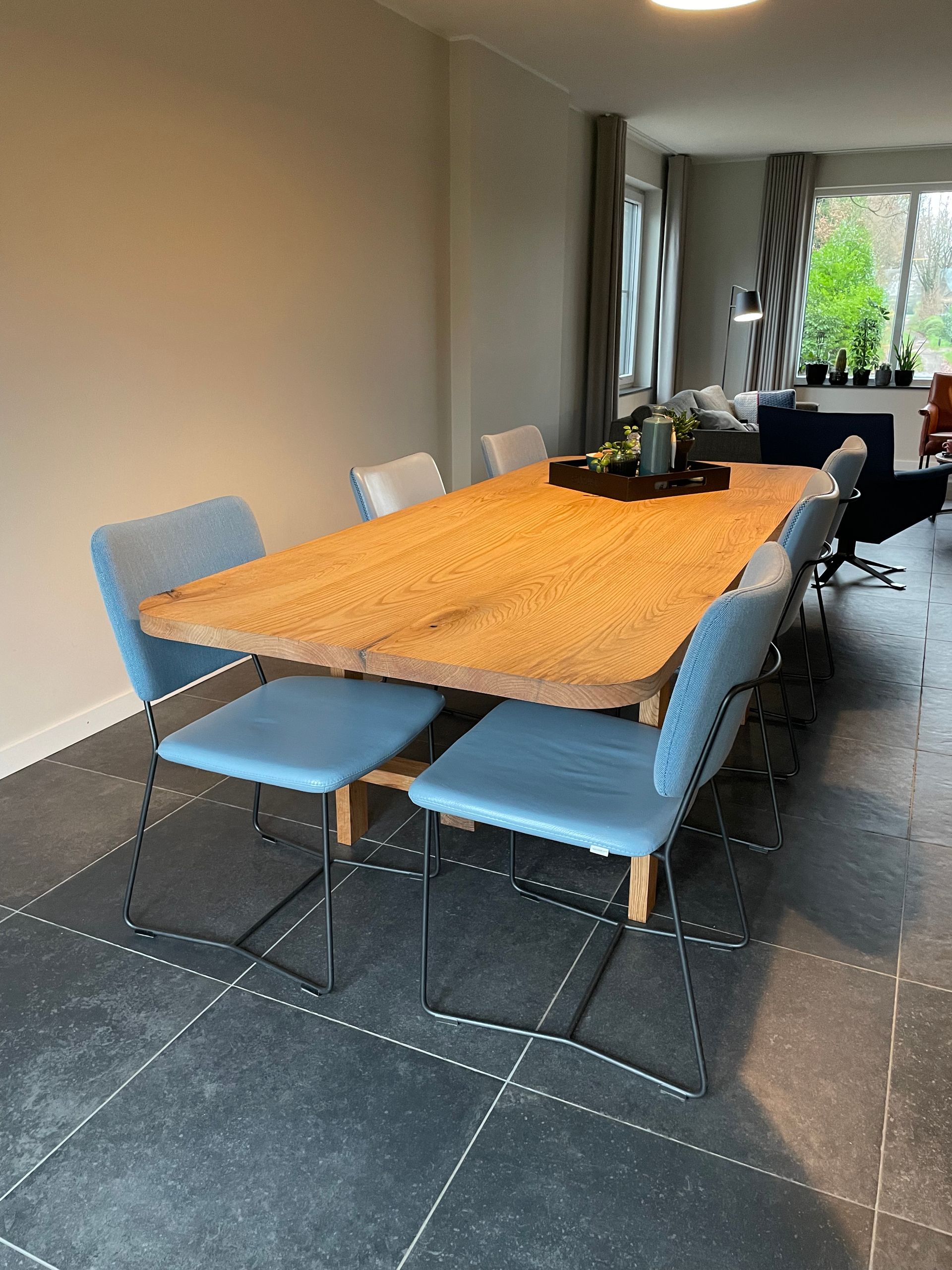 Een eetkamer met een houten tafel en blauwe stoelen.