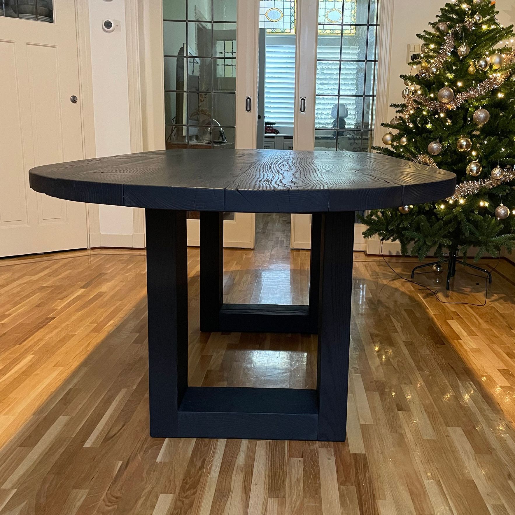 Een ronde tafel met een kerstboom op de achtergrond