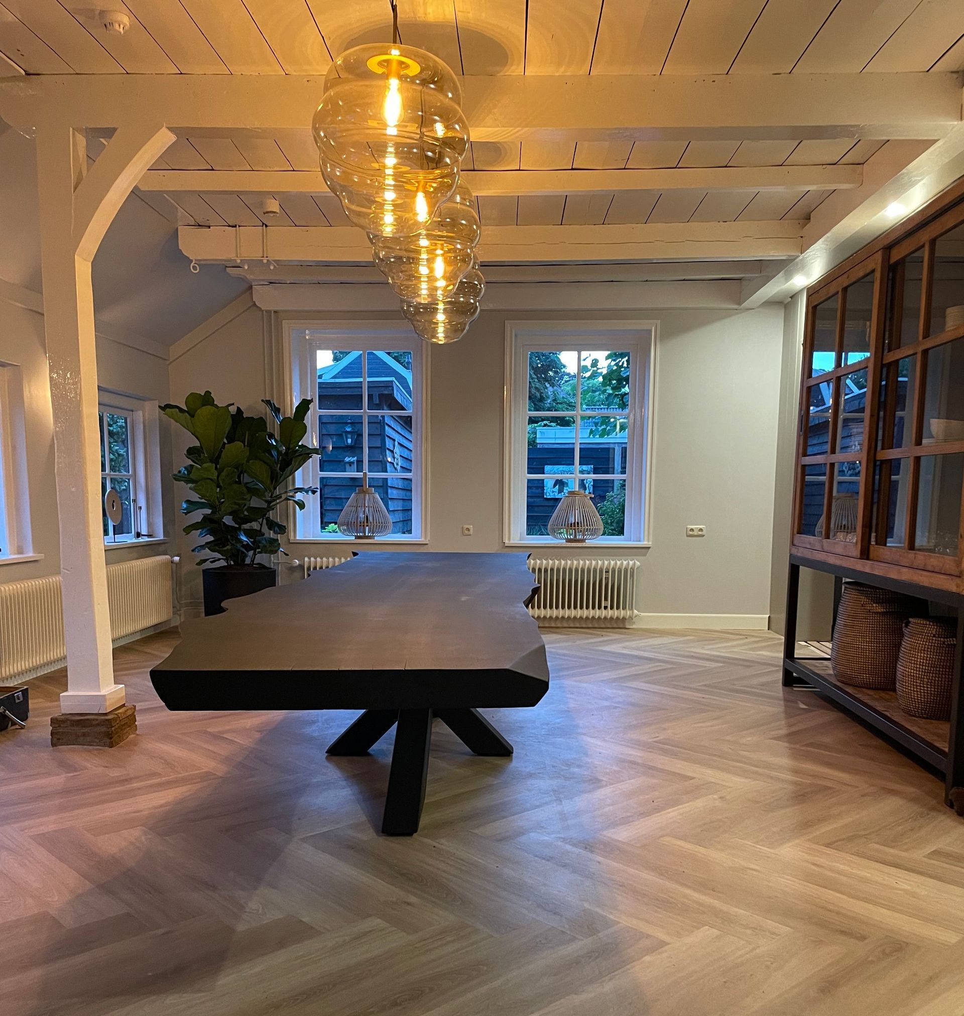 Een grote tafel in een kamer met veel ramen