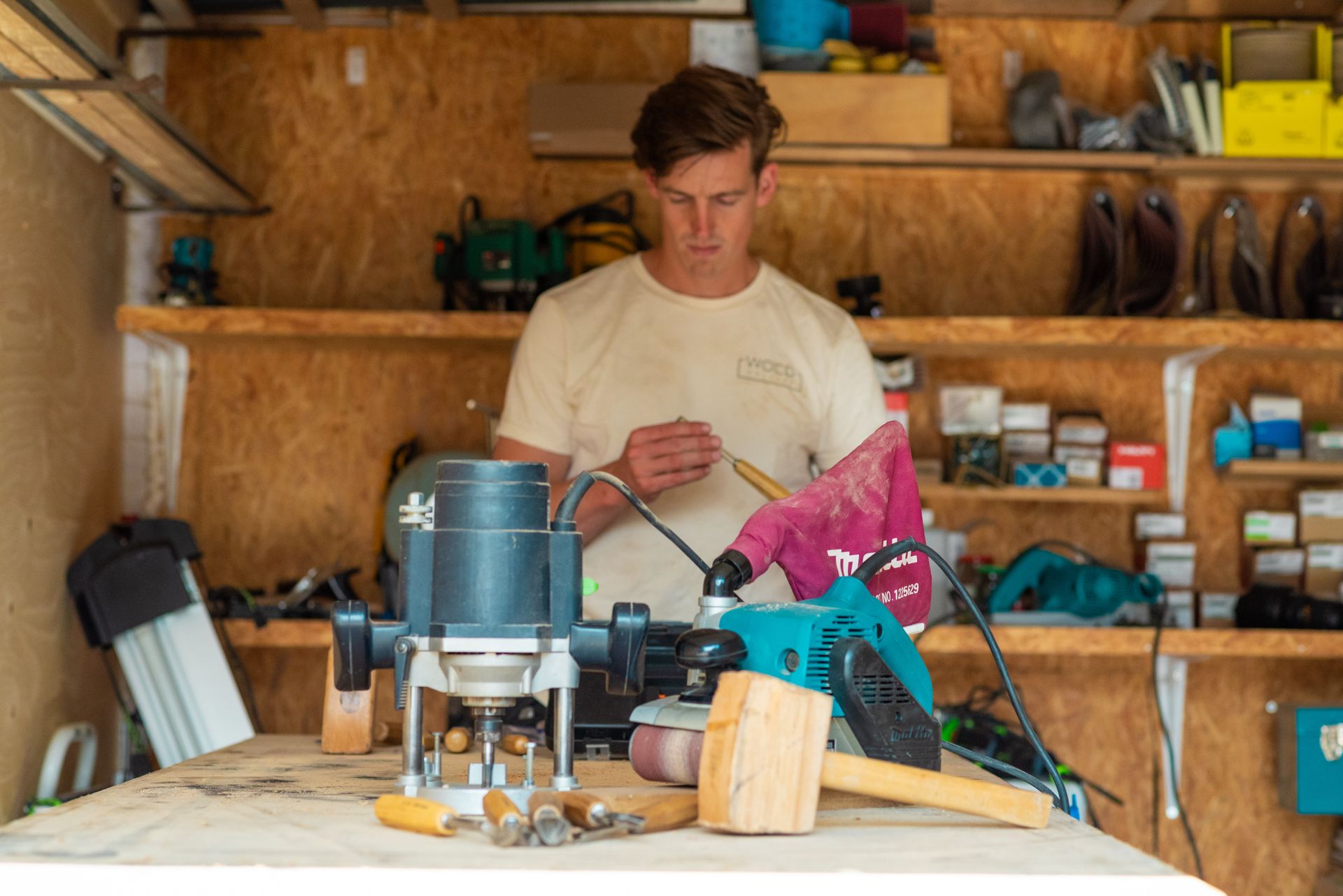Een man werkt aan een router in een garage.