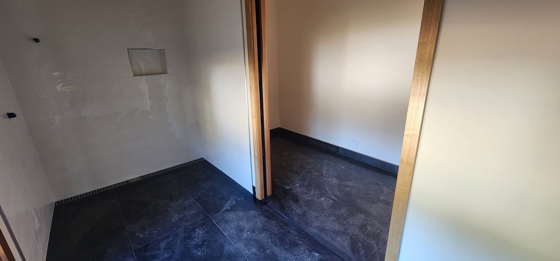 Small unfinished room with exposed wooden studs, bare walls, and dark flooring on the left.