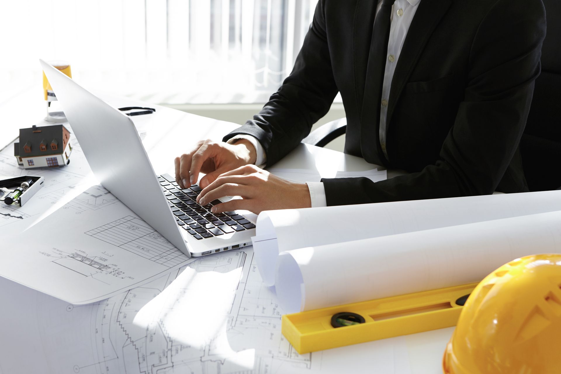 A man in a suit is typing on a laptop computer.
